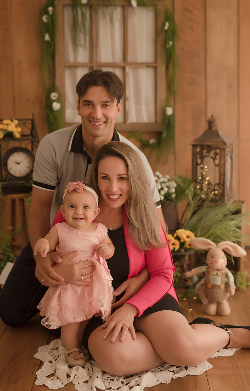 foto de bebe em caxias do sul fotografa morgana perini bebe de vestido rosa no colo da mae com o pai