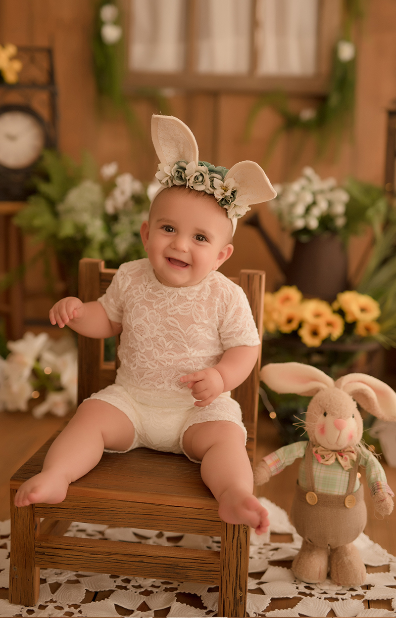 foto de bebe em caxias do sul fotografa morgana perini bebe sentada na cadeira sorrindo cenário de pascoa