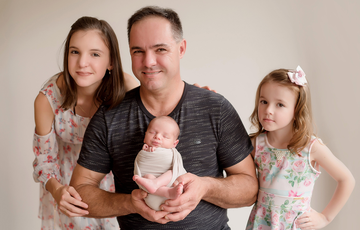 foto de newborn em caxias do sul fotografa morgana perini bebe no colo do pai com as duas irmas