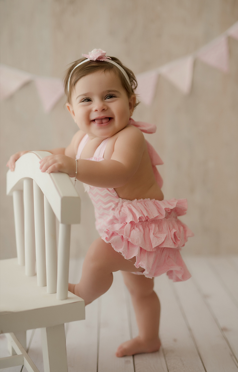 foto de bebe em caxias do sul fotografa morgana perini bebe com vestido rosa segurando se em cadeira