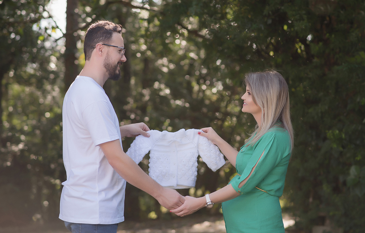 foto de gestante em caxias do sul fotografa morgana perini pais segurando um casaco do bebe