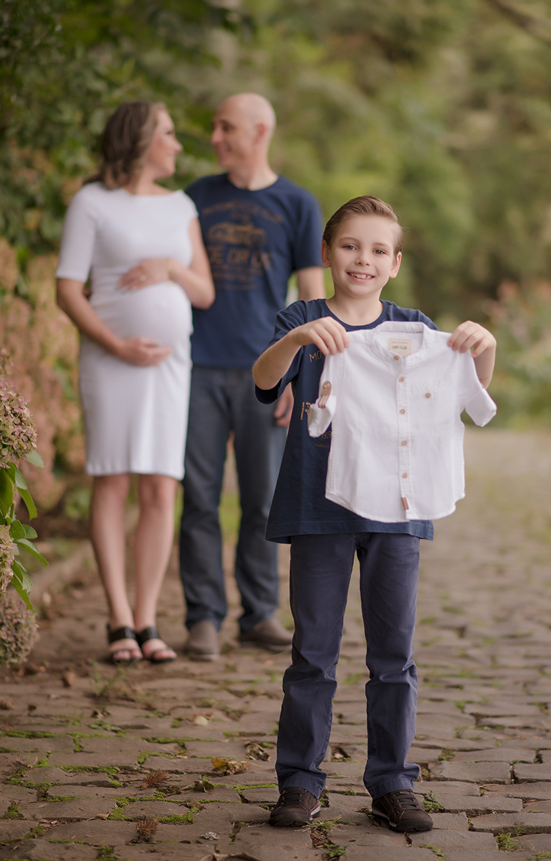 foto de gestante em caxias do sul fotografa morgana perini filho mais velho segurando roupa do irmao