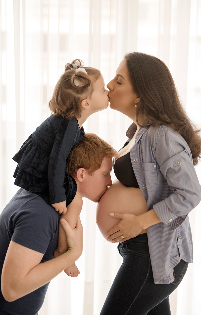 foto de bebe em caxias do sul fotografa morgana perini pai beijando a barriga da mae e filha dando beijo na mae