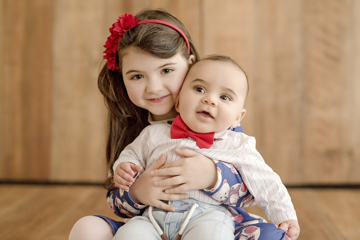 foto de bebe em caxias do sul fotografa morgana perini irma com irmão no colo com enfeites vermelhos