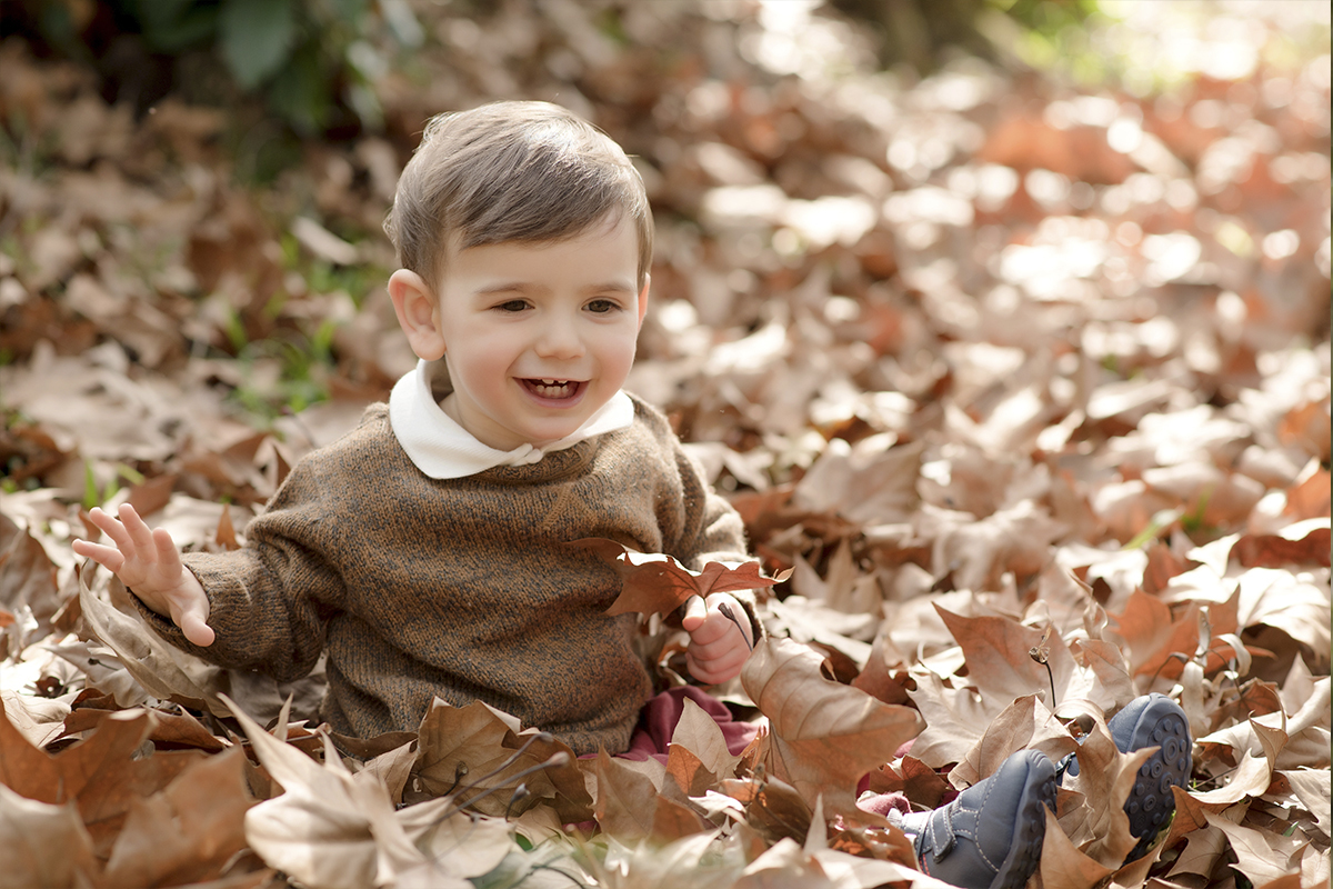 foto de criança em caxias do sul fotografa morgana perini criança brincando com folhas secas de arvore