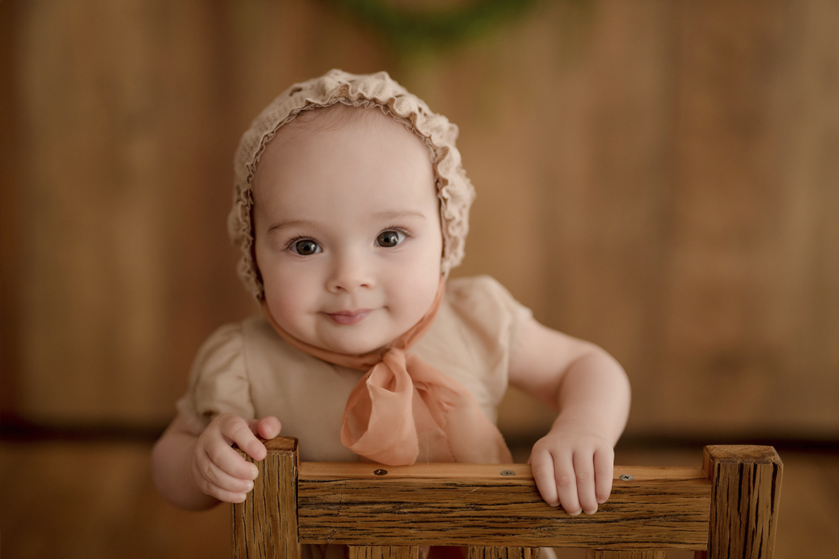 foto de bebe em caxias do sul fotografa morgana perini bebe se  segurando em cadeira marrom
