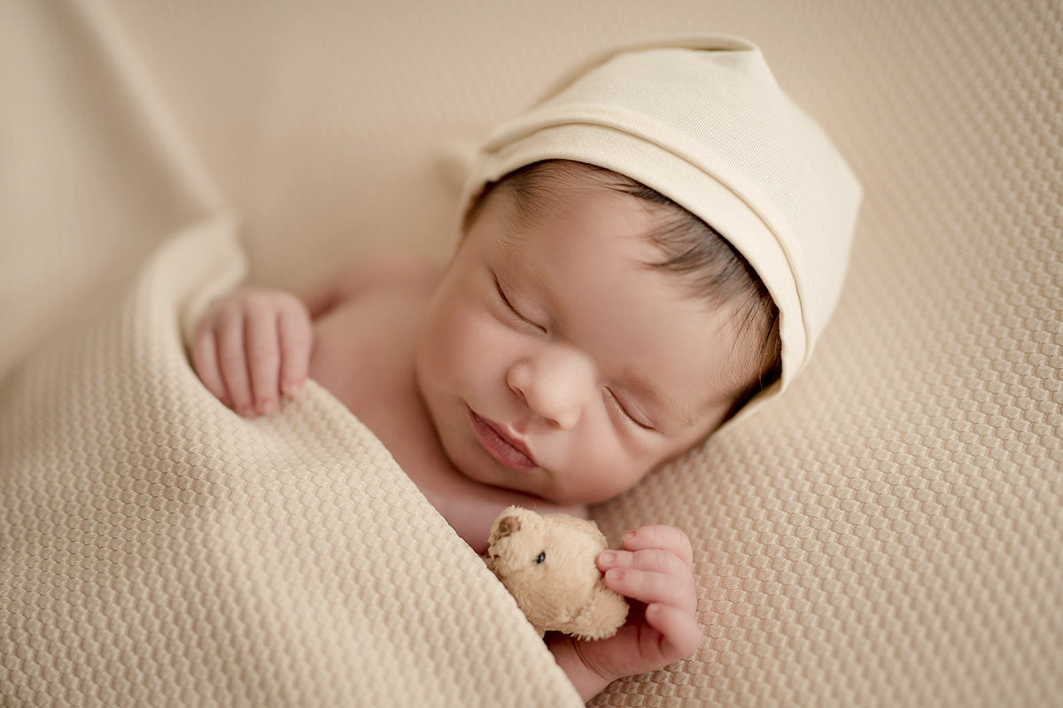 Foto newborn em caxias do sul fotografa morgana perini bebe segurando urso touca de dormi
