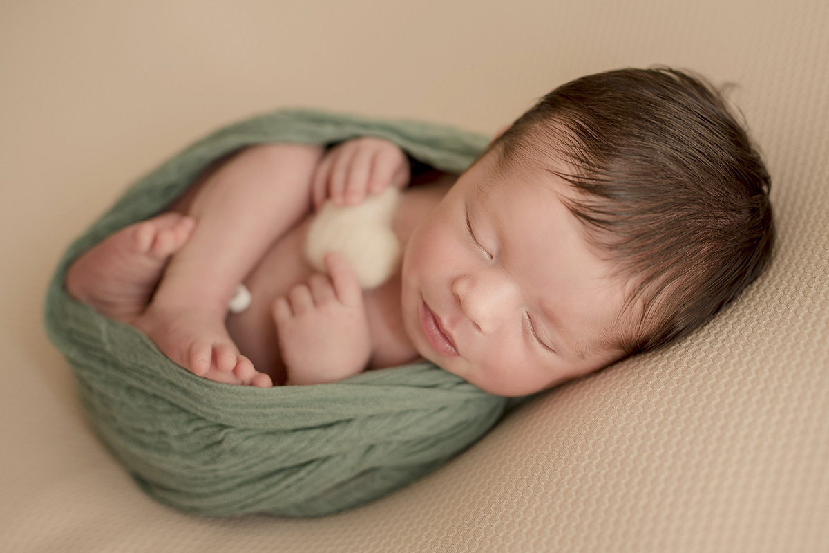 Foto newborn em caxias do sul fotografa morgana perini bebe enrolado tecido verde