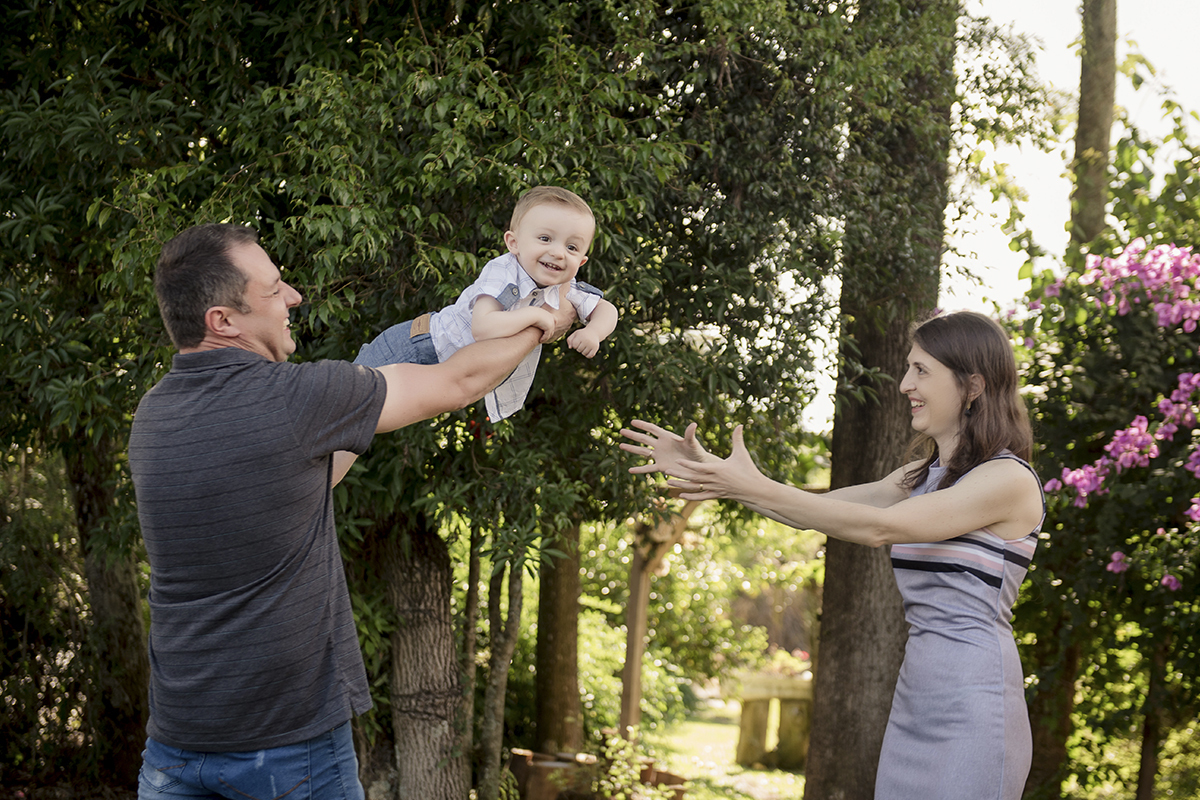Foto criança em caxias do sul fotografa morgana perini menino voando colo pai e mae olhando