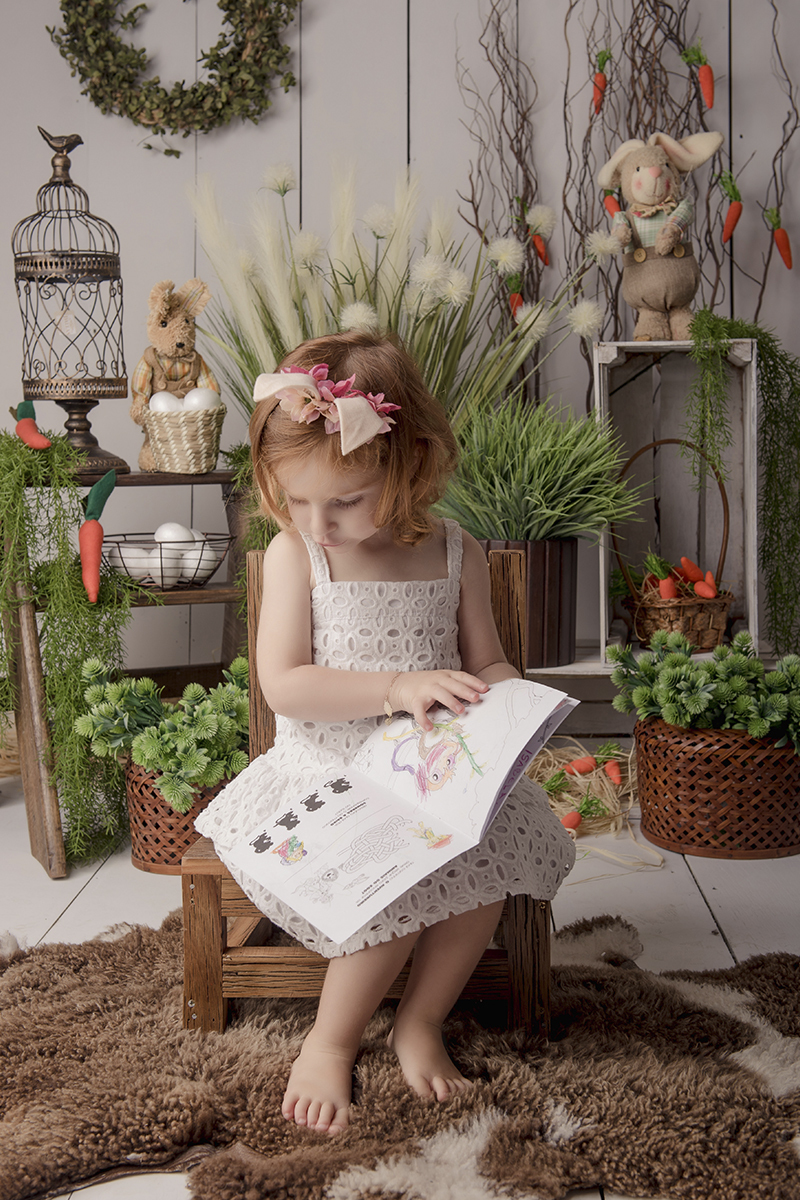 Foto criança em caxias do sul fotografa morgana perini menina com livro de coloris pascoa