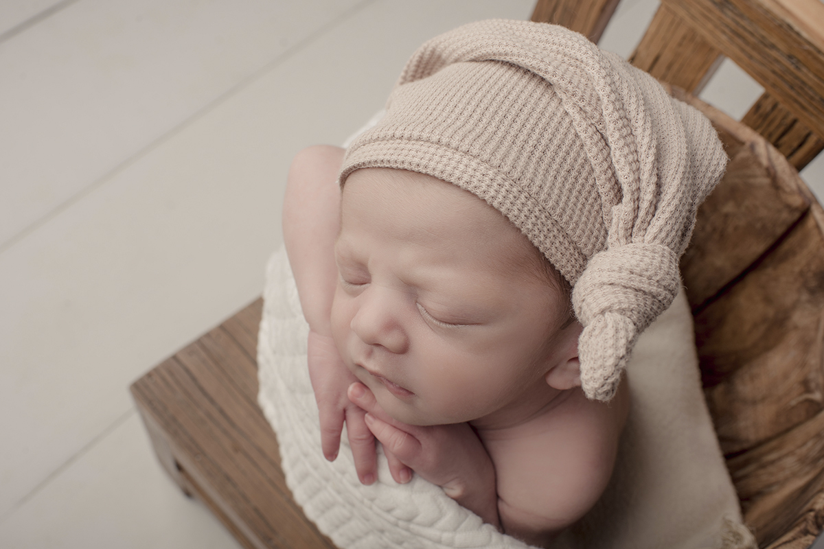 Foto newborn em caxias do sul fotografa morgana perini bebe touca bege cadeira marrom