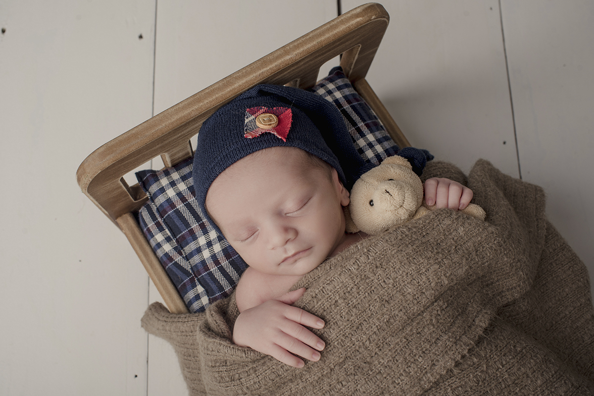 Foto newborn em caxias do sul fotografa morgana perini bebe cama marrom e xadrez azul