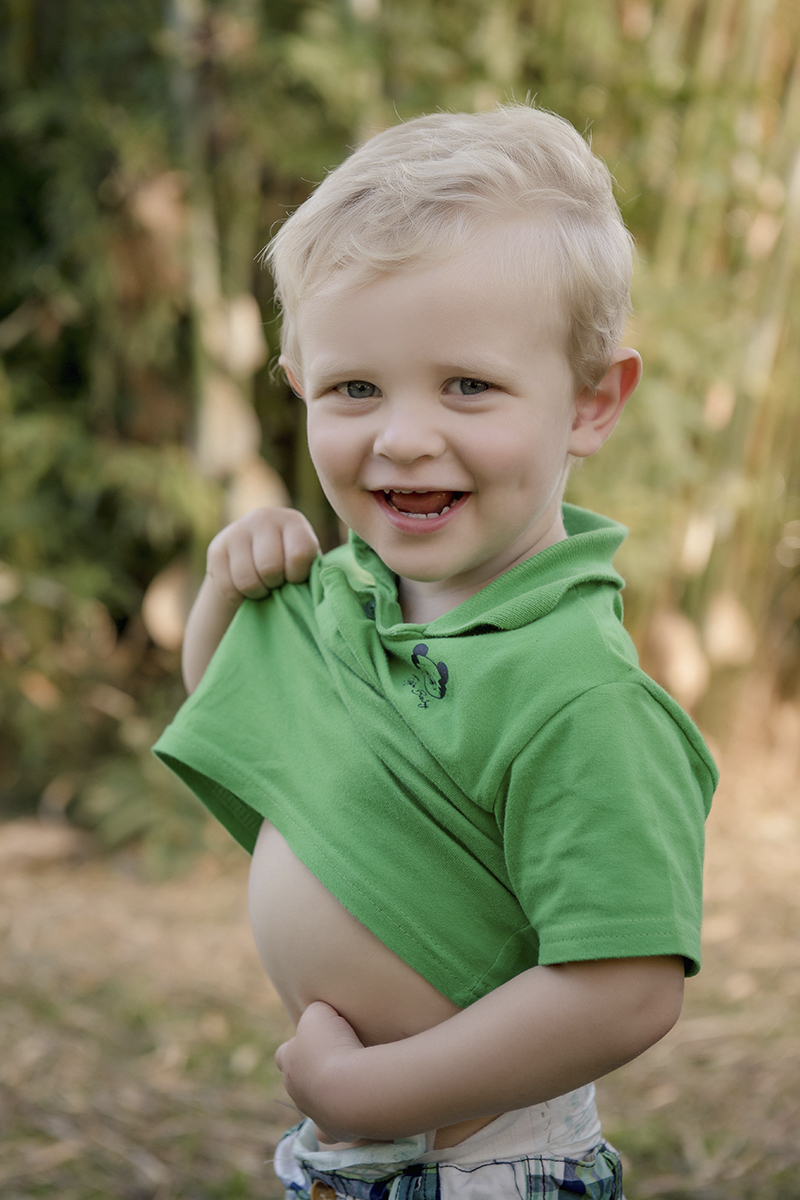 Foto de bebe em caxias do sul fotografa morgana perini levantando a camisa verde sorrindo