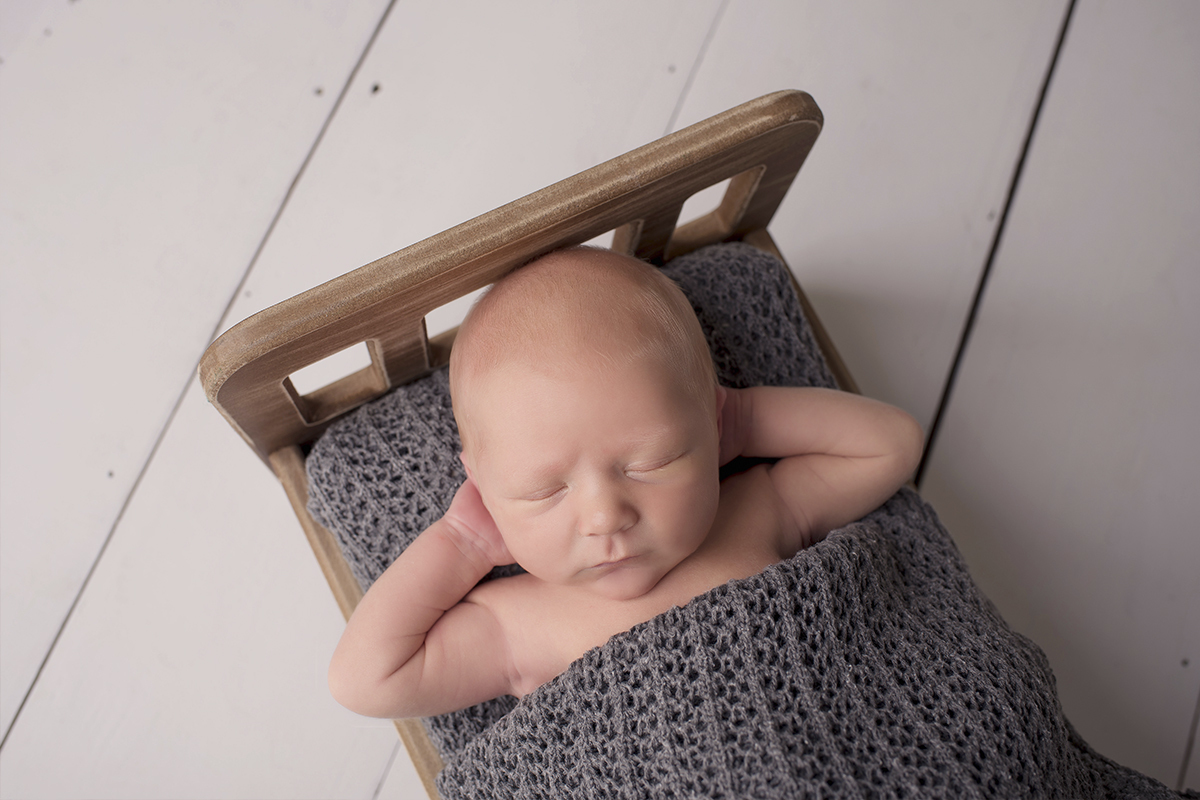 Foto newborn em caxias do sul fotografa morgana perini bebe cama de madeira braços na cabela