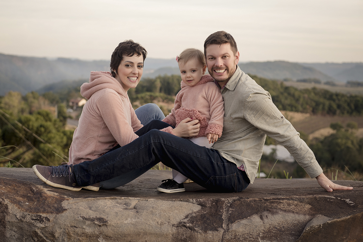 Foto de familia em caxias do sul fotografa morgana perini pais sentados pedra grande com menina