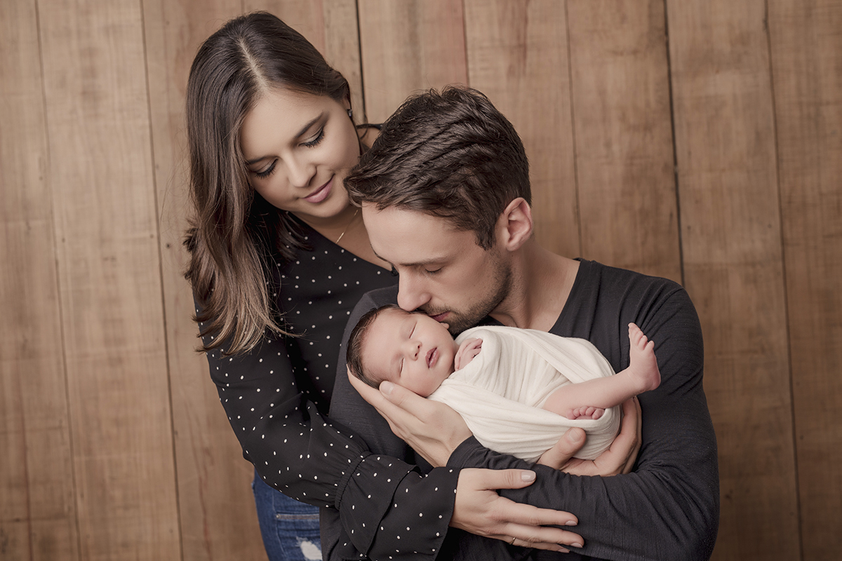 Foto newborn em caxias do sul fotografa morgana perini pai beijando bebe tecido branco pais de roupa preta