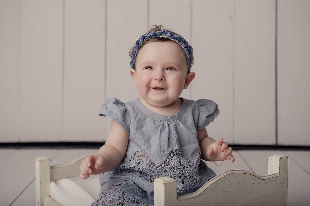 Foto de bebe em caxias do sul fotografa morgana perini menina vestido azul cama branca de madeira