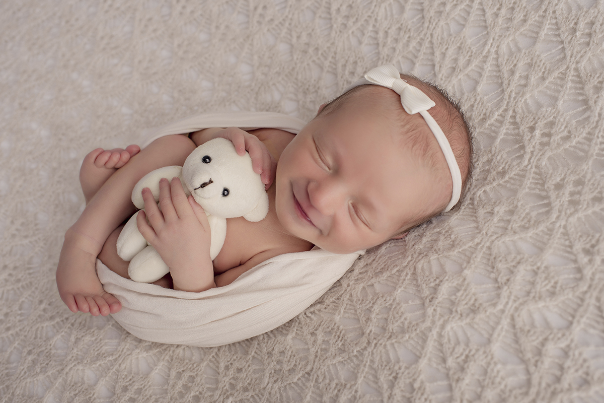 Foto newborn em caxias do sul fotografa morgana perini enrolada sorrindo urso branco
