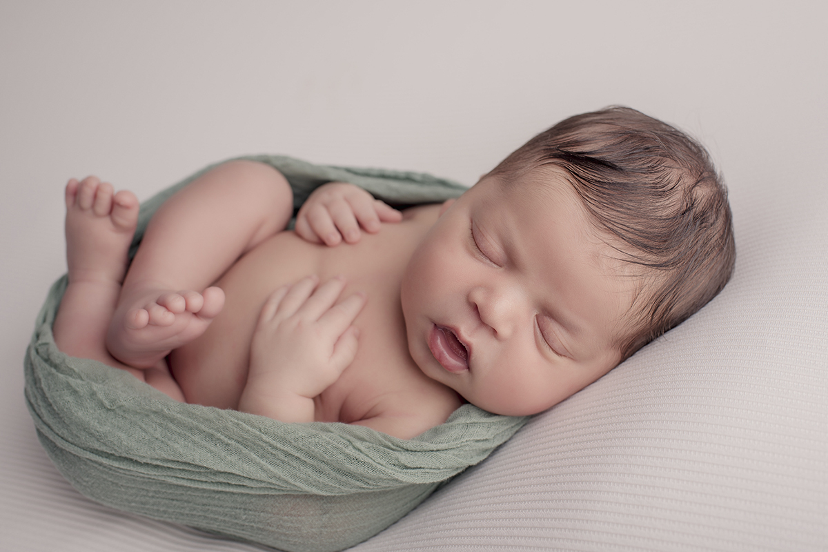 Foto newborn em caxias do sul fotografa morgana perini enrolado tecido verde gorfinho