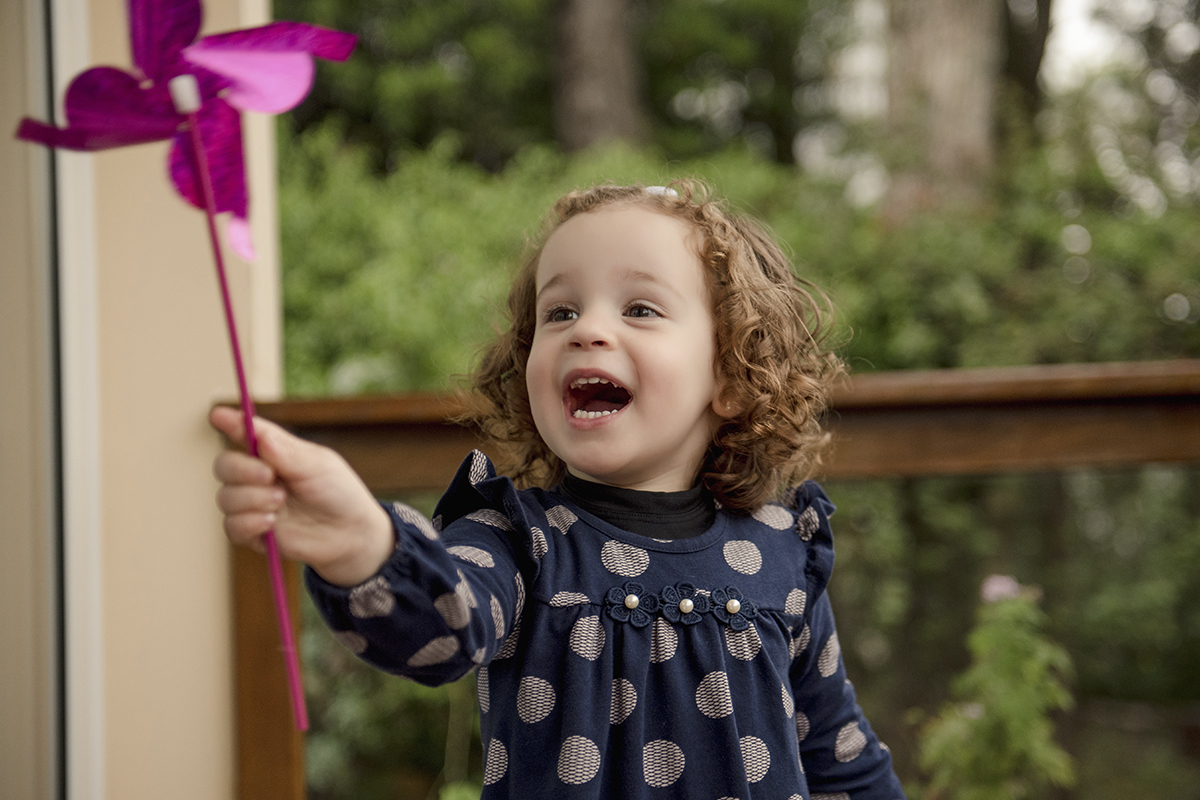 menina vestido azul bolinhas com catavento rosa