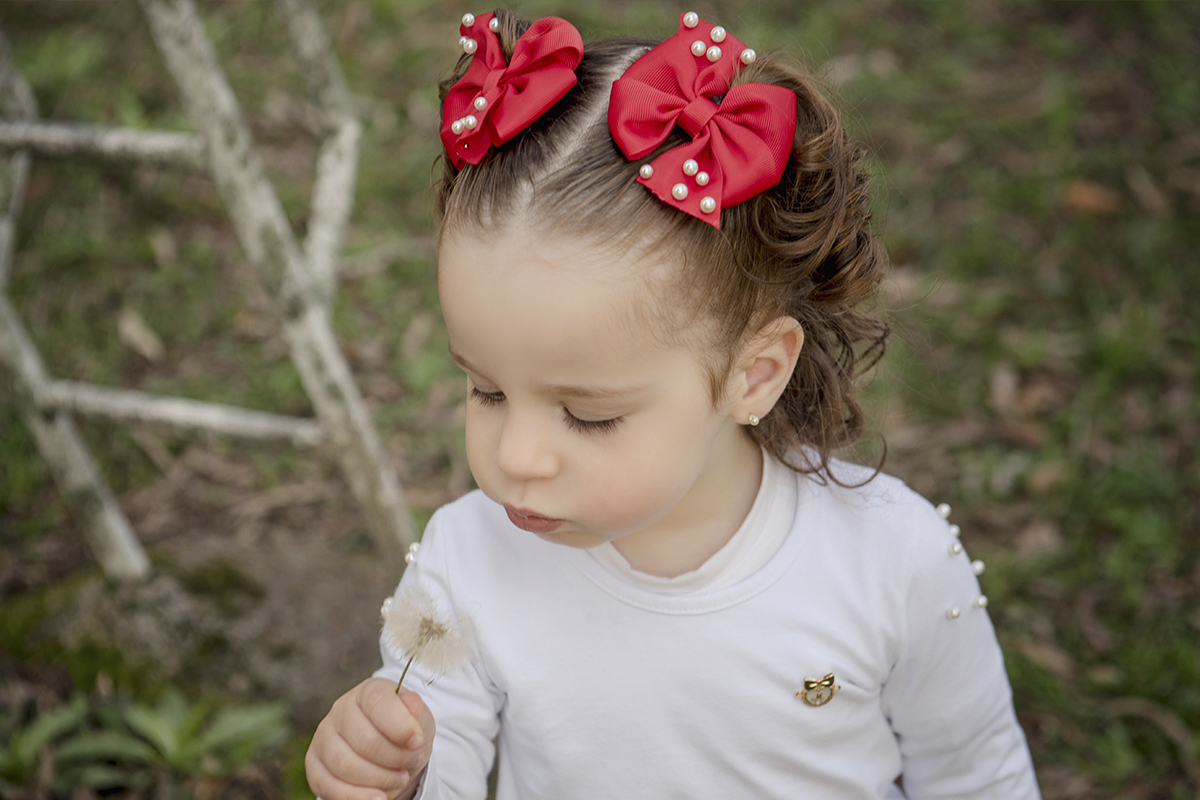 menina vestido azul bolinhas menina laco vermelho asoprando 