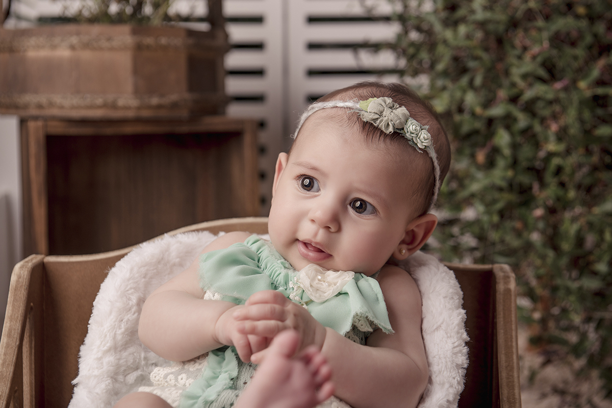 menina roupa verde brincando com os pes