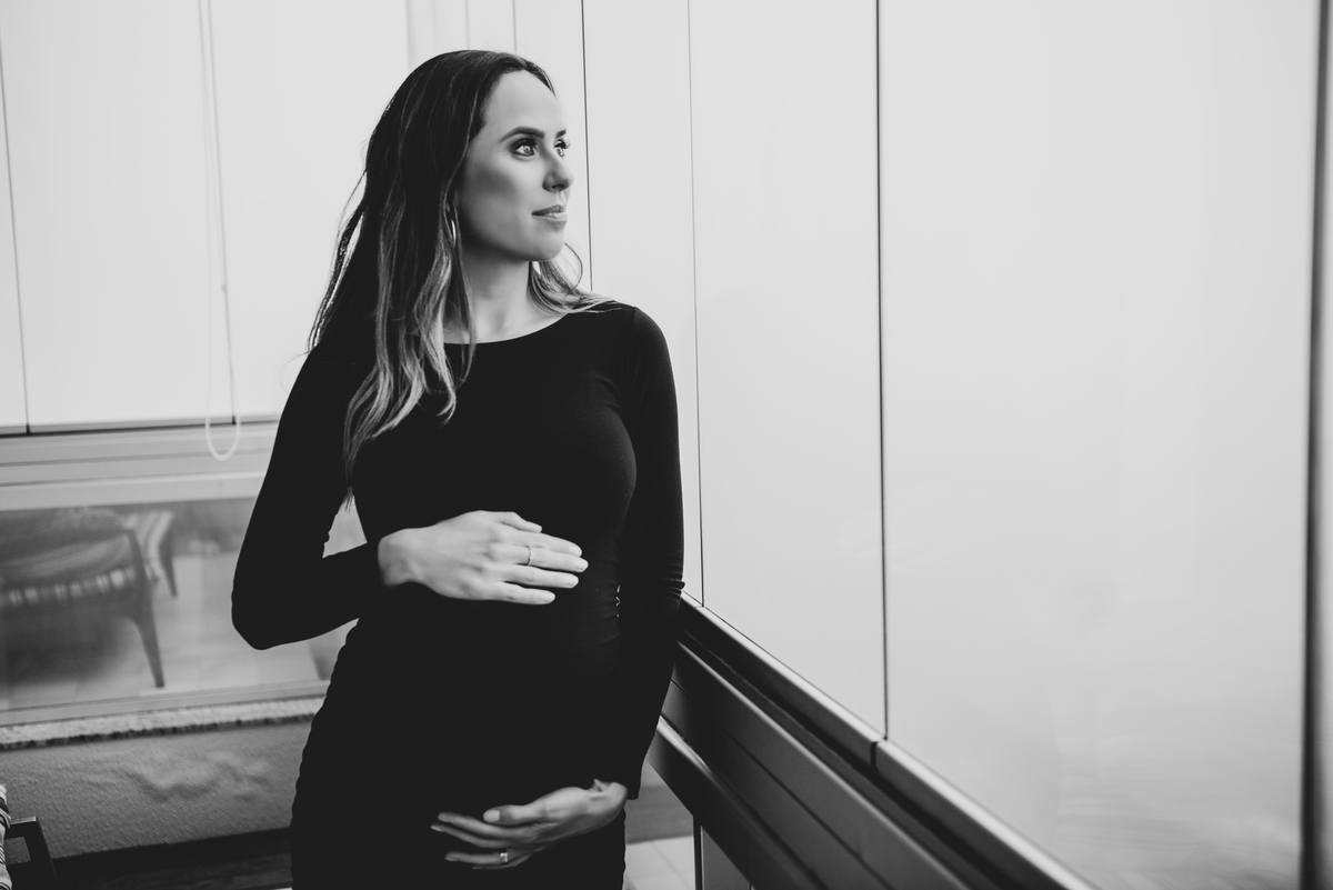 gestante maos na barriga olhando janela