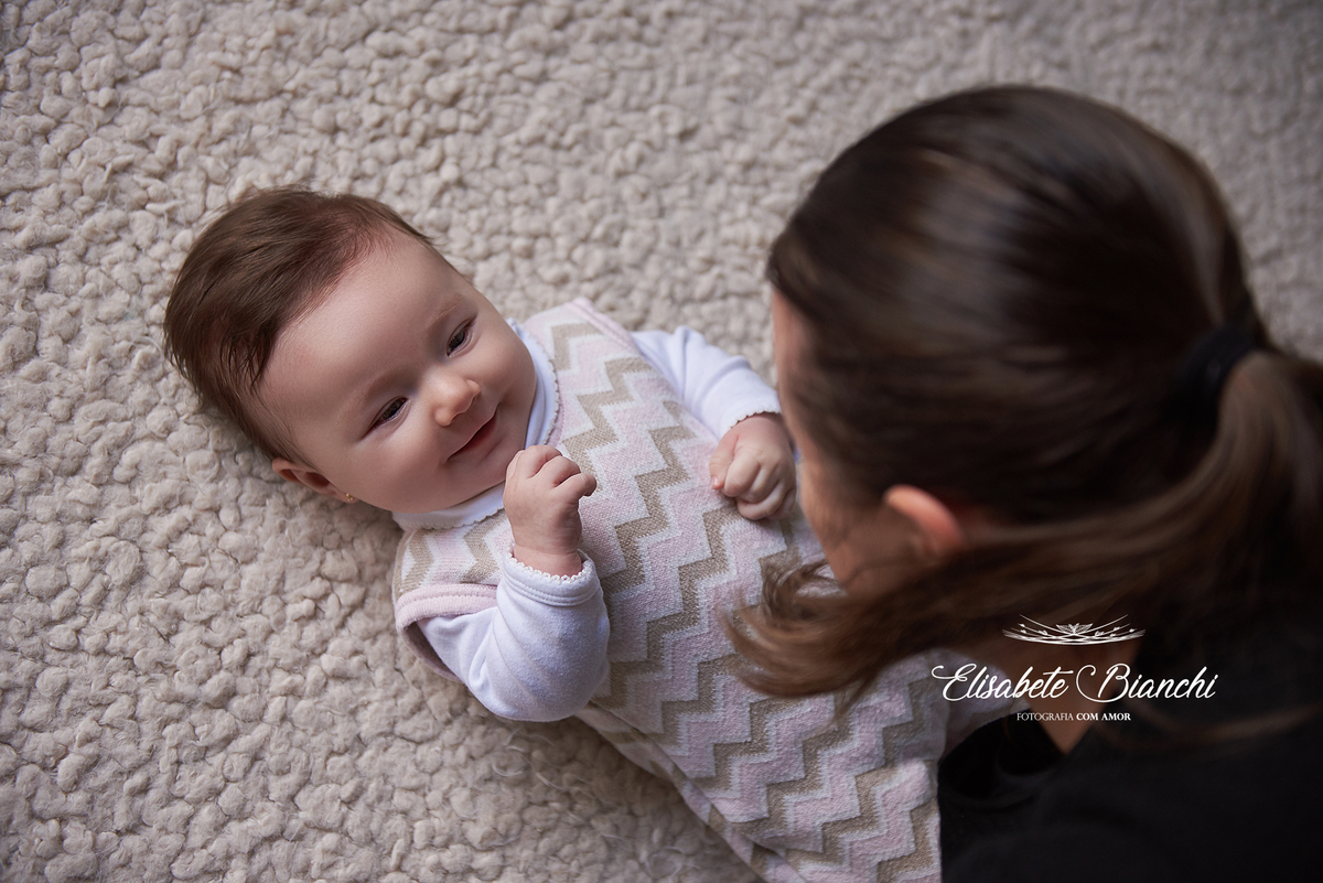 Bebê olhando e sorrindo para a mãe que conversa com ela, em acompanhamento de fotos trimestral, em Caxias do Sul.