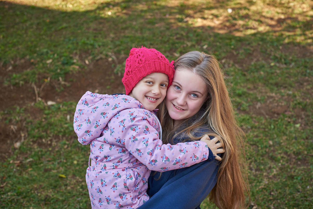 Menina com câncer no colo de sua irmã mais velha, em ensaio em Caxias do Sul - RS.