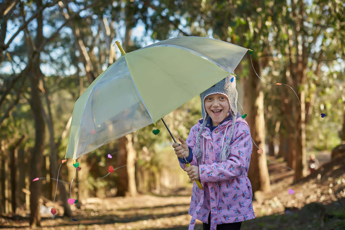 Menina lutando contra o câncer, brincando com uma sombrinha com chuva de corações de papel, em Caxias do Sul - RS.