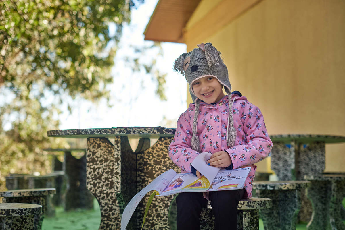 Menina com câncer lendo livro que os amigos escreveram fazendo ela protagonista da história, como heroína, em Caxias do Sul - RS.