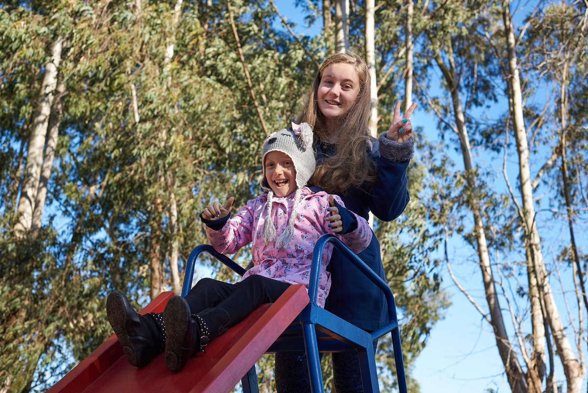 Menina com câncer brincando com sua irmã no escorregador do parquinho, em Caxias do Sul - RS.