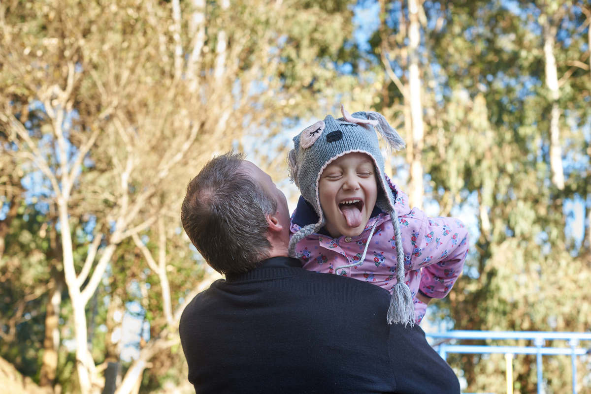 Menina com câncer, no colo do pai, com língua para fora, em Caxias do Sul - RS.
