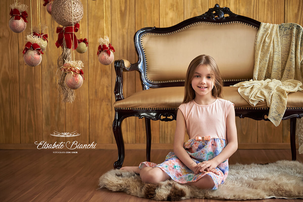 Menina sentada na frente de uma namoradeira Luiz XV, em ensaio natalino, em Caxias do Sul - RS.