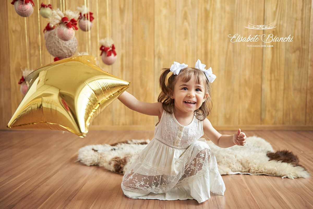 Menina brincando com estrela dourada, em ensaio de natal, em estúdio, Caxias do Sul - RS.