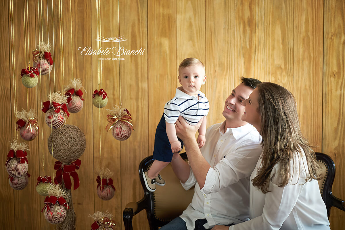 Mini ensaio de Natal 2018 com família levantando bebê, em estúdio, Caxias do Sul - RS