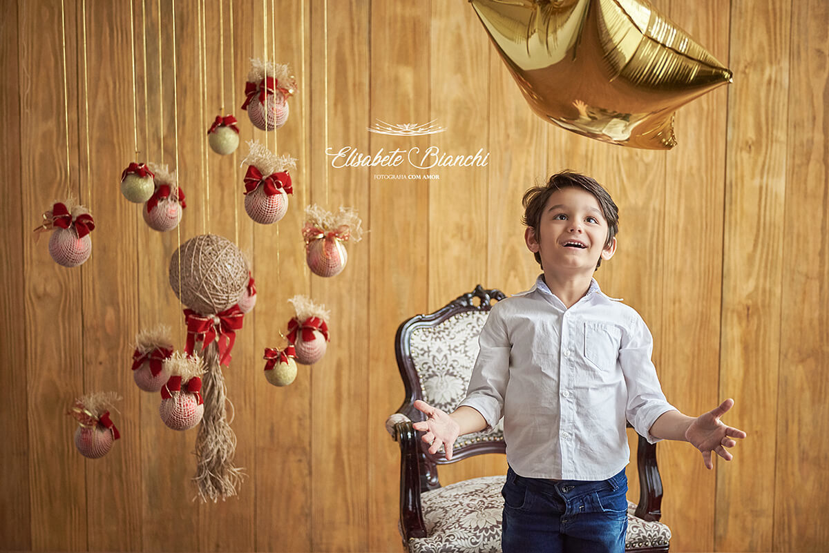 Menino brincando com estrela dourada, em ensaio de natal, em estúdio, Caxias do Sul - RS.