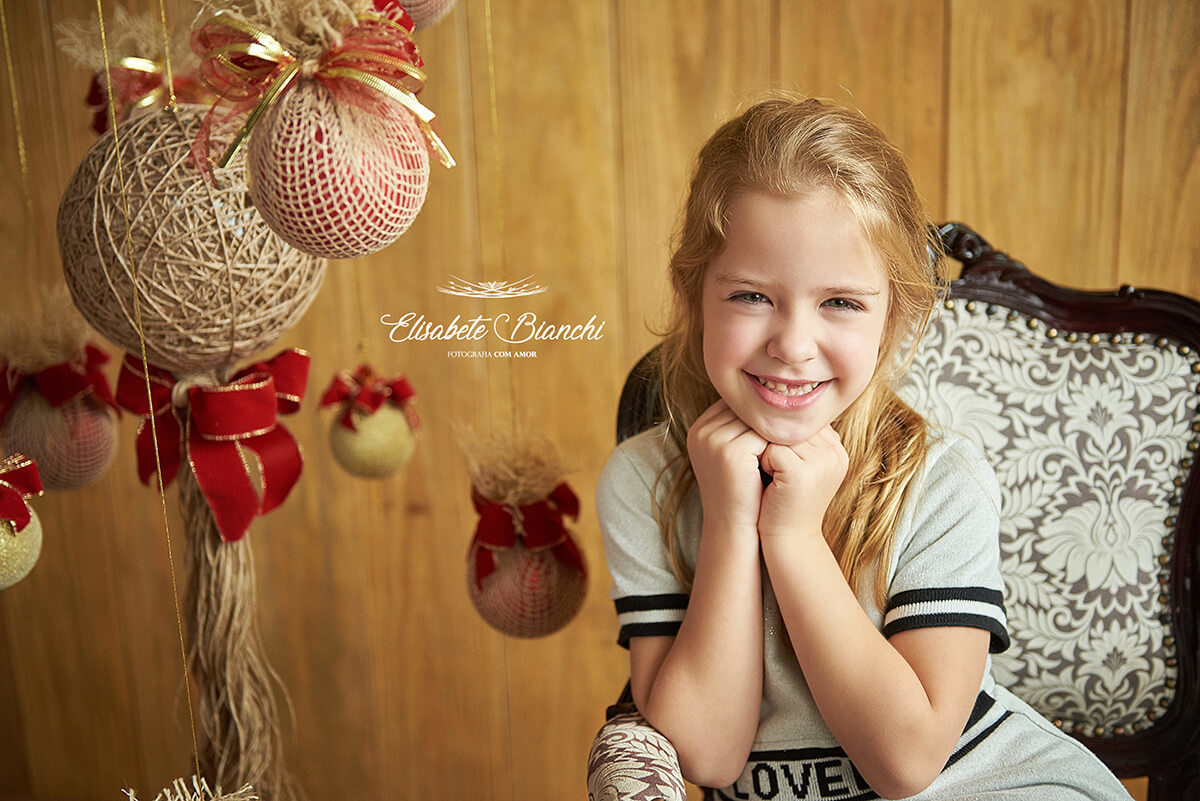 Menina sentada em poltrona Luiz XV, em ensaio de natal, em estúdio, Caxias do Sul - RS.