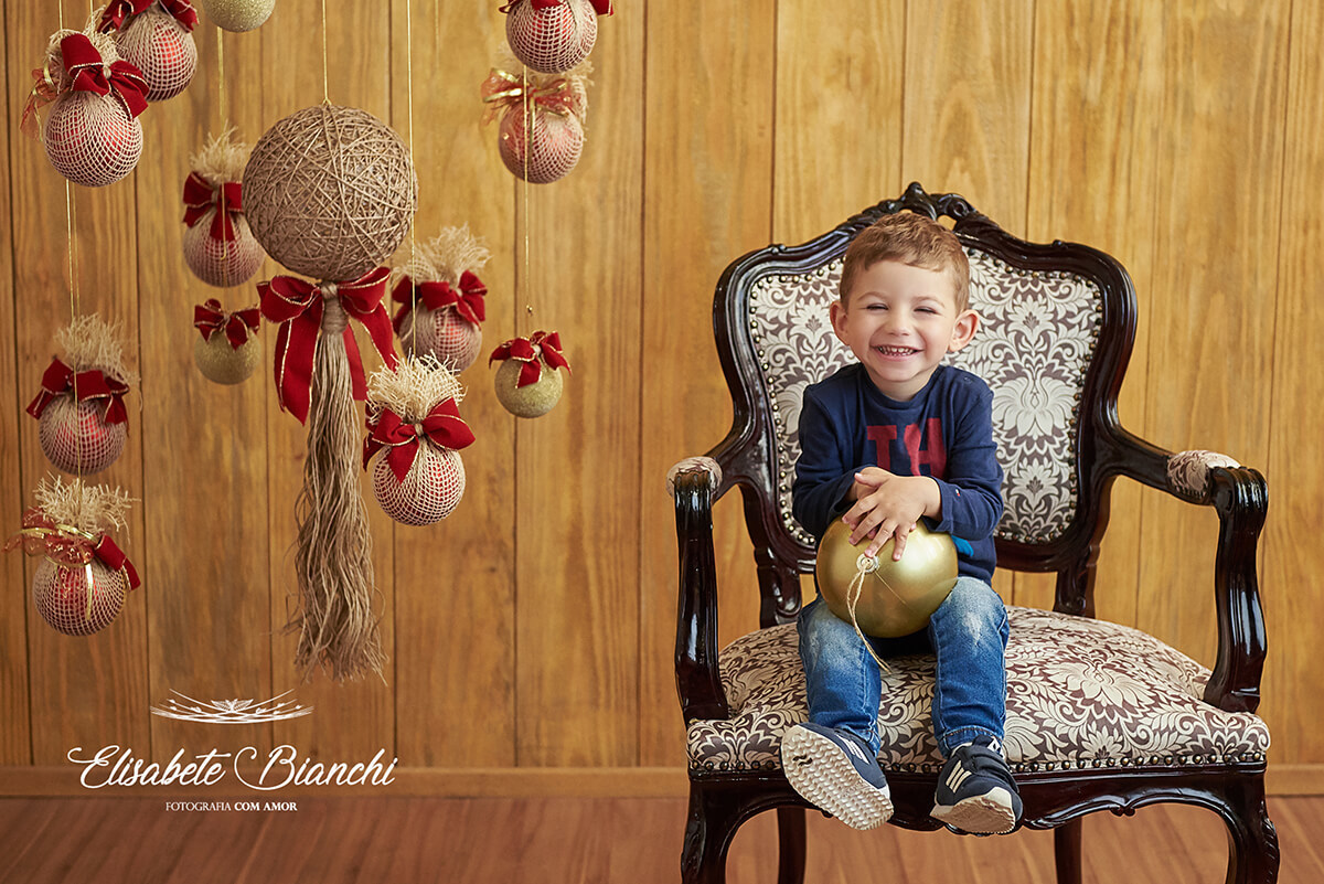 Criança sentada em poltrona Luiz XV, em ensaio de natal, em estúdio, Caxias do Sul - RS.