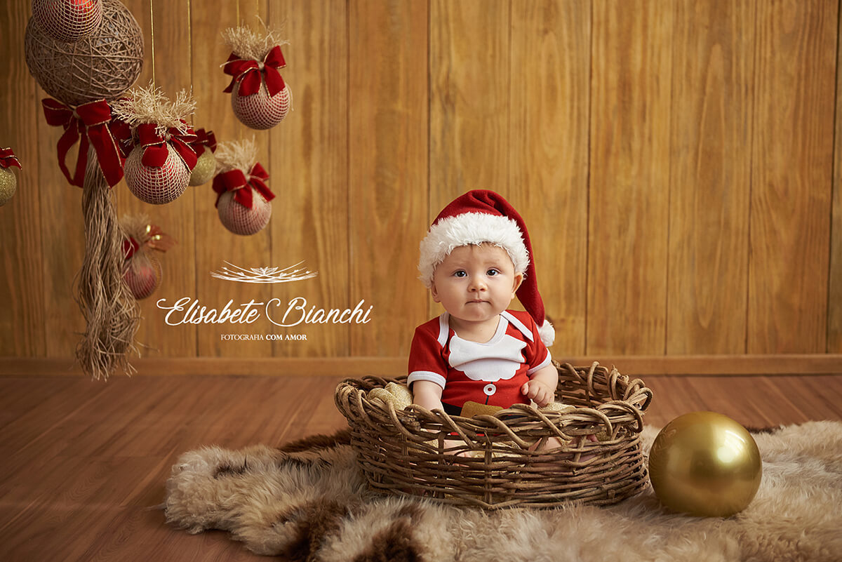 Bebê dentro de cesto com touca de Papai Noel, em retrato de natal, em estúdio, Caxias do Sul - RS.