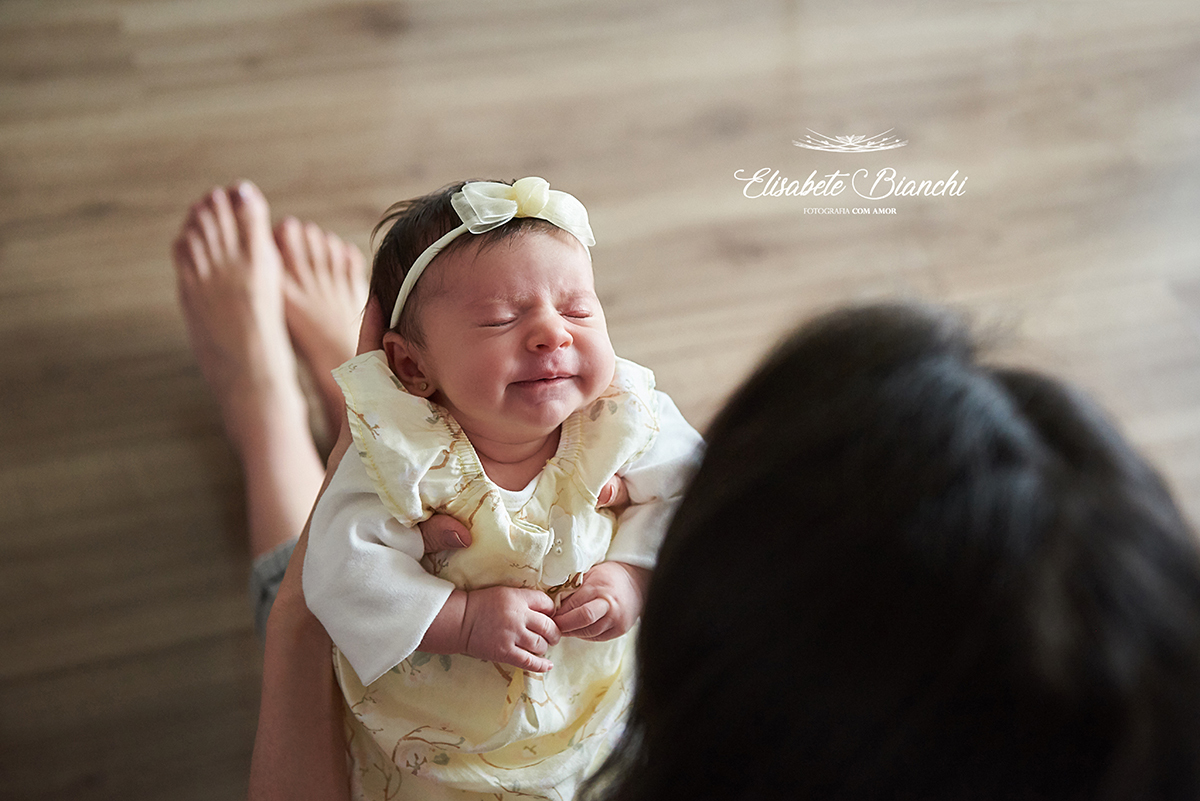 Filha no colo da mãe, reclamando por mamá, em ensaio lifestyle de acompanhamento bebê, em Caxias do Sul - RS.