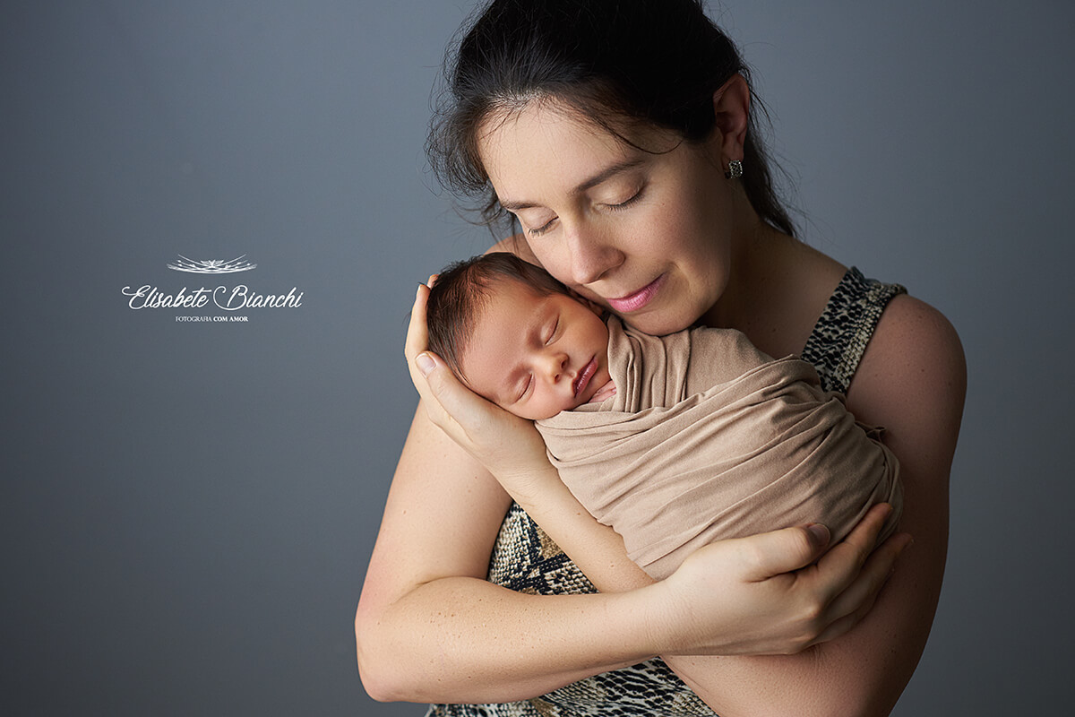 Recém-nascido no colo da mãe, de olhos fechados, em ensaio newborn, Caxias do Sul - RS.