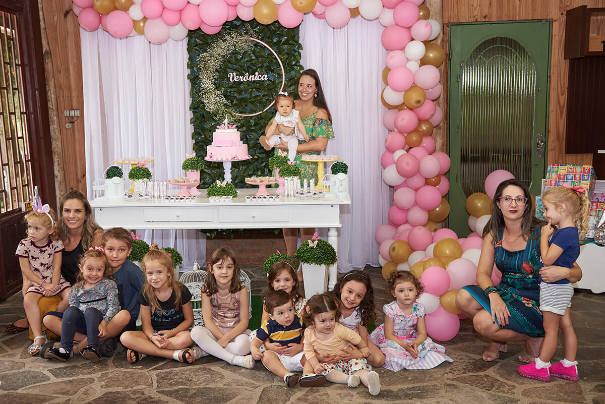 Crianças em frente à mesa da do bolo da festa de aniversário de 1 ano da bebê, em Caxias do Sul - RS.