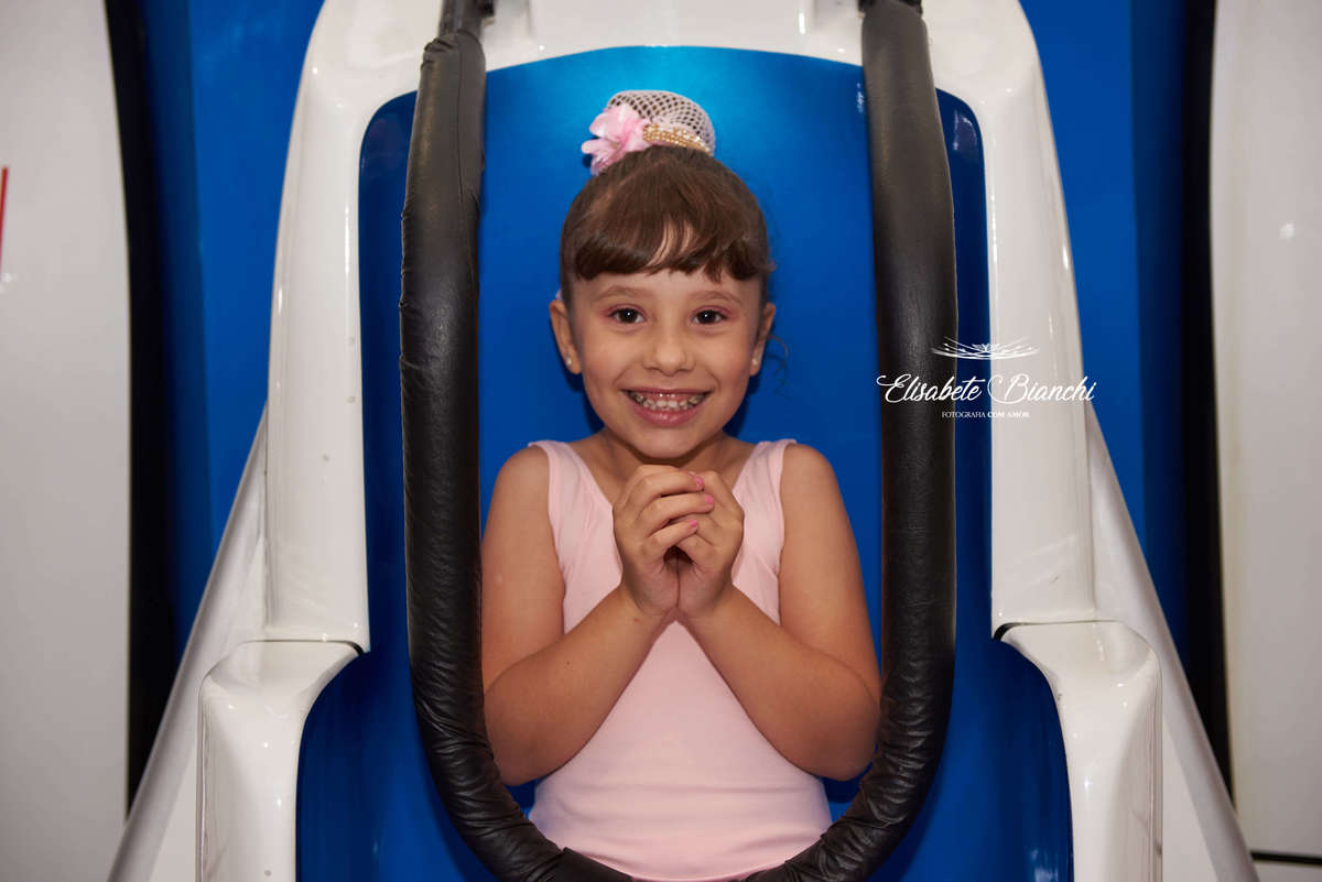 Aniversariante ansiosa, sentada no brinquedo elevador que cai, na festa de aniversário de 6 anos, na casa de festas Gato & Topo, em Caxias do Sul - RS.
