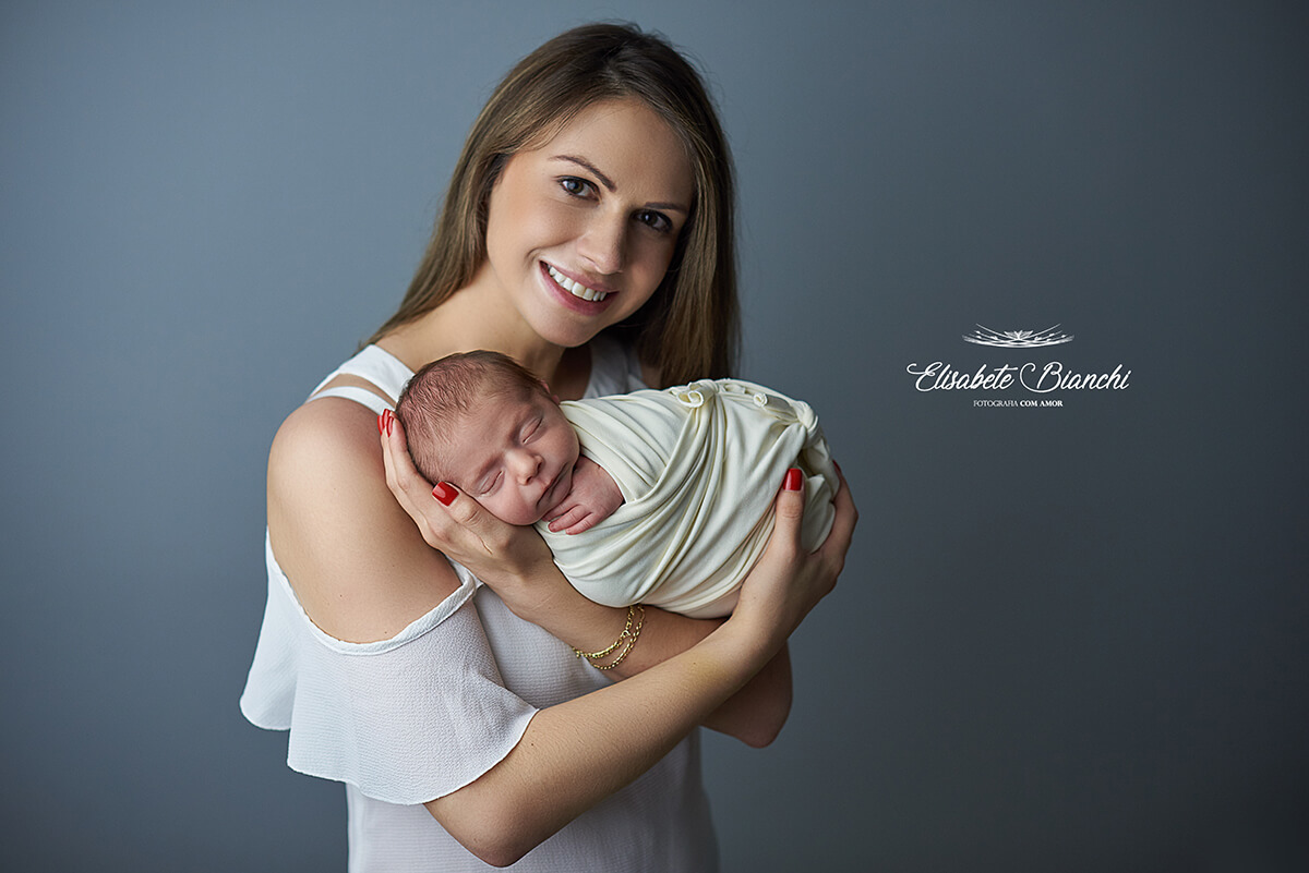 Bebê recém-nascido enroladinho no colo da mãe, no ensaio Newborn, em Caxias do Sul - RS