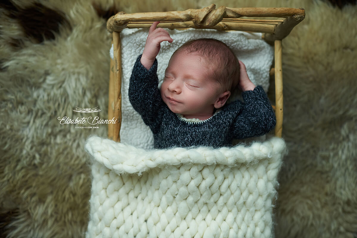 Bebê recém-nascido deitado na caminha, esticando o bracinho, se espreguiçando ou alongando o corpo, no ensaio Newborn, em Caxias do Sul - RS