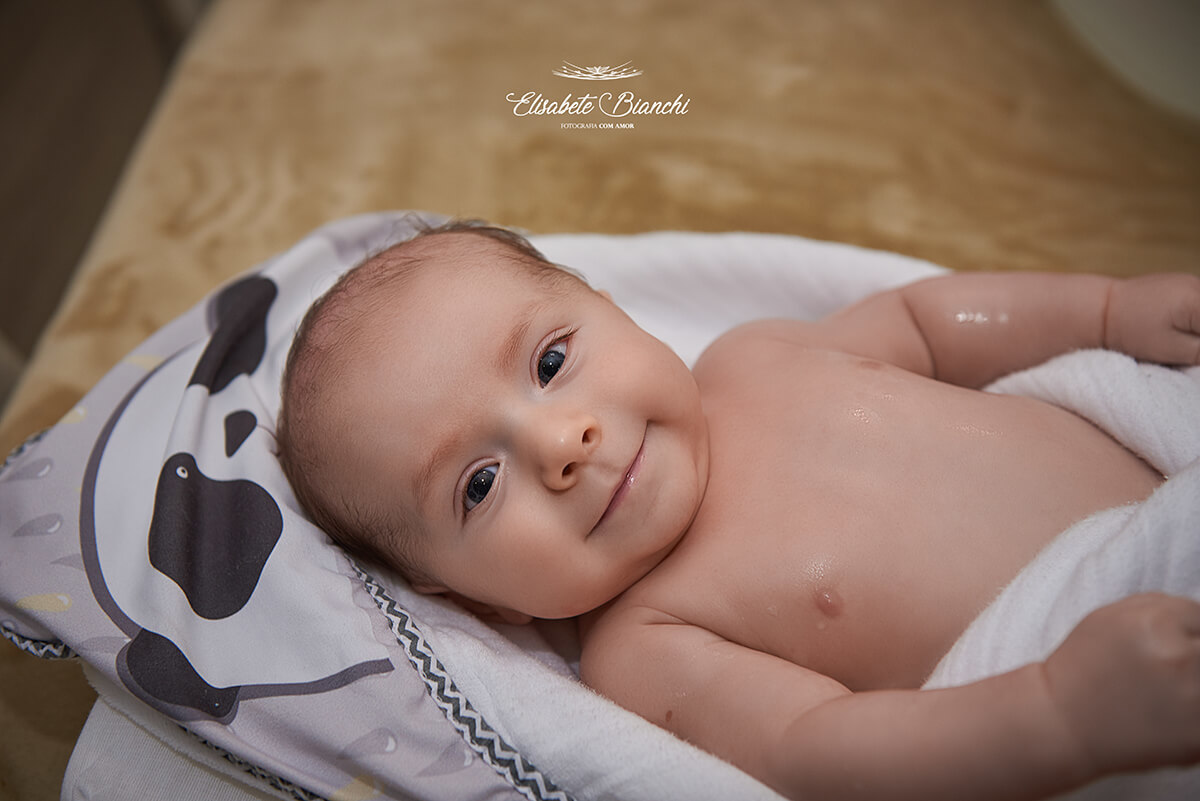 Bebê de 3 meses sorrindo, saído do banho, em ensaio lifestyle de acompanhamento, em São Marcos, RS.