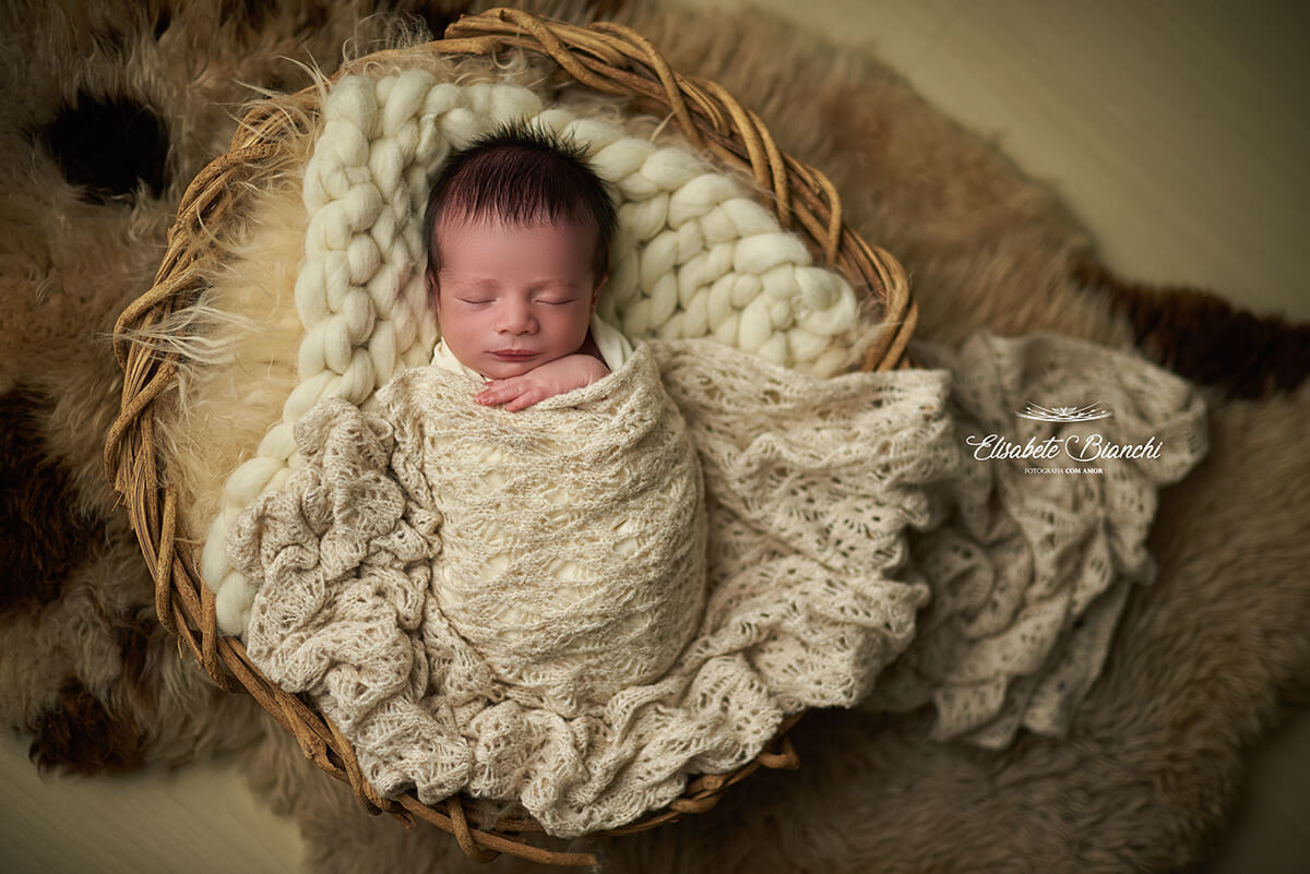 Bebê recém-nascido dentro de cesto, enroladinho, no ensaio newborn, em Caxias do Sul - RS.