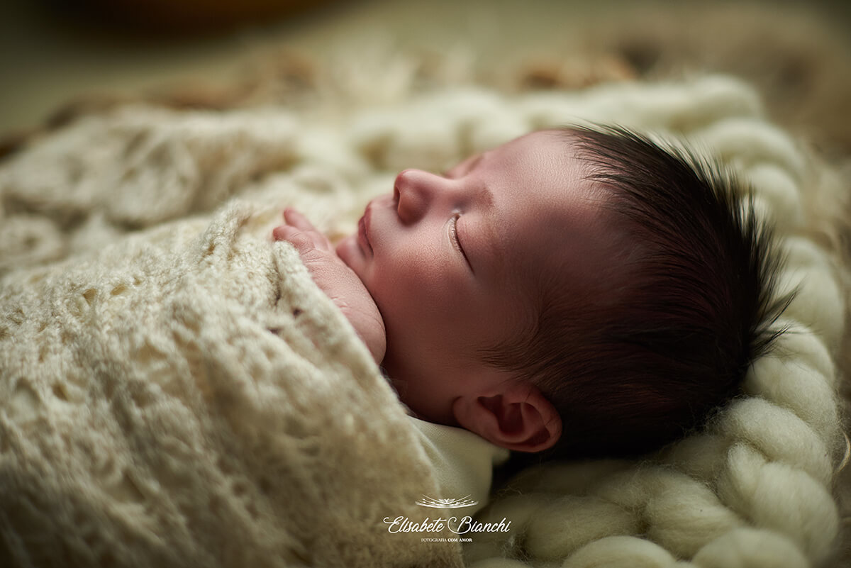 Perfil de bebê recém-nascido, enroladinho, no ensaio newborn, em Caxias do Sul - RS.