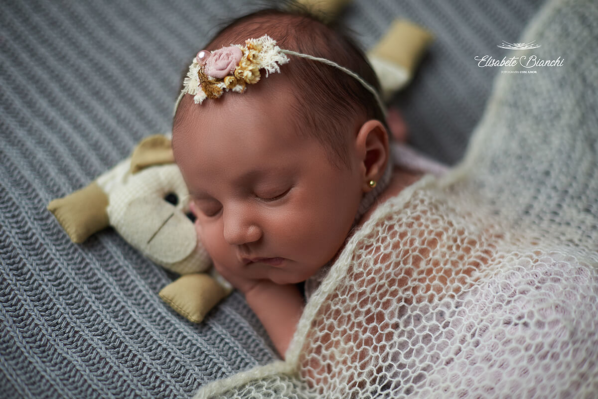 Bebê recém-nascida dormindo sobre almofadinha de cólica, e coberta com uma mantinha telada, em ensaio newborn, Caxias do Sul - RS